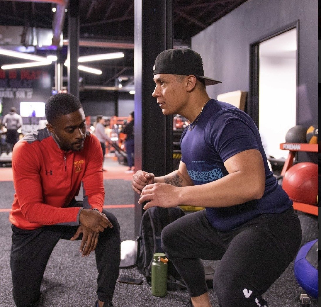 Coach assessing an athlete's squat position in the gym